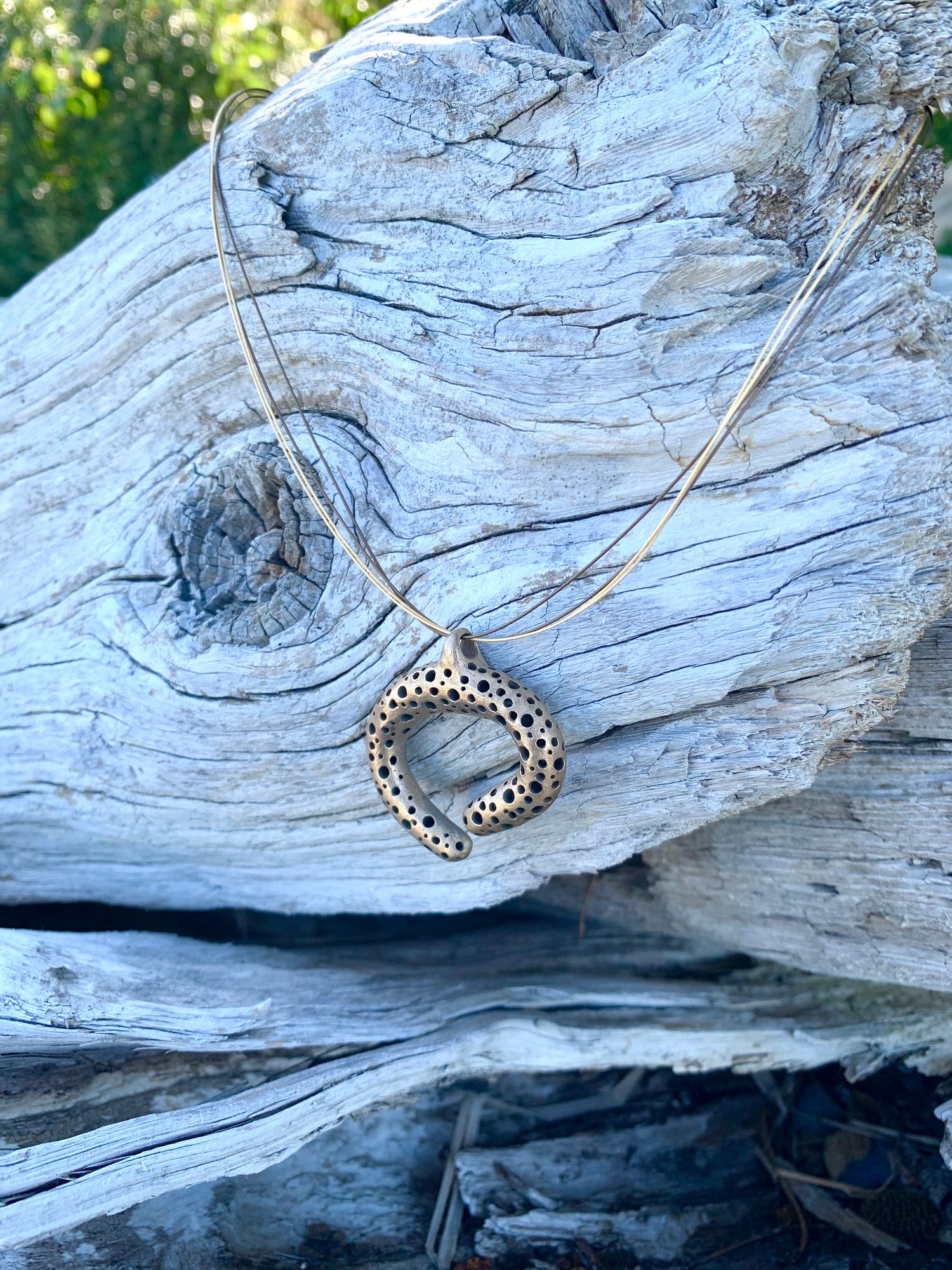 Bronze pendant on driftwood