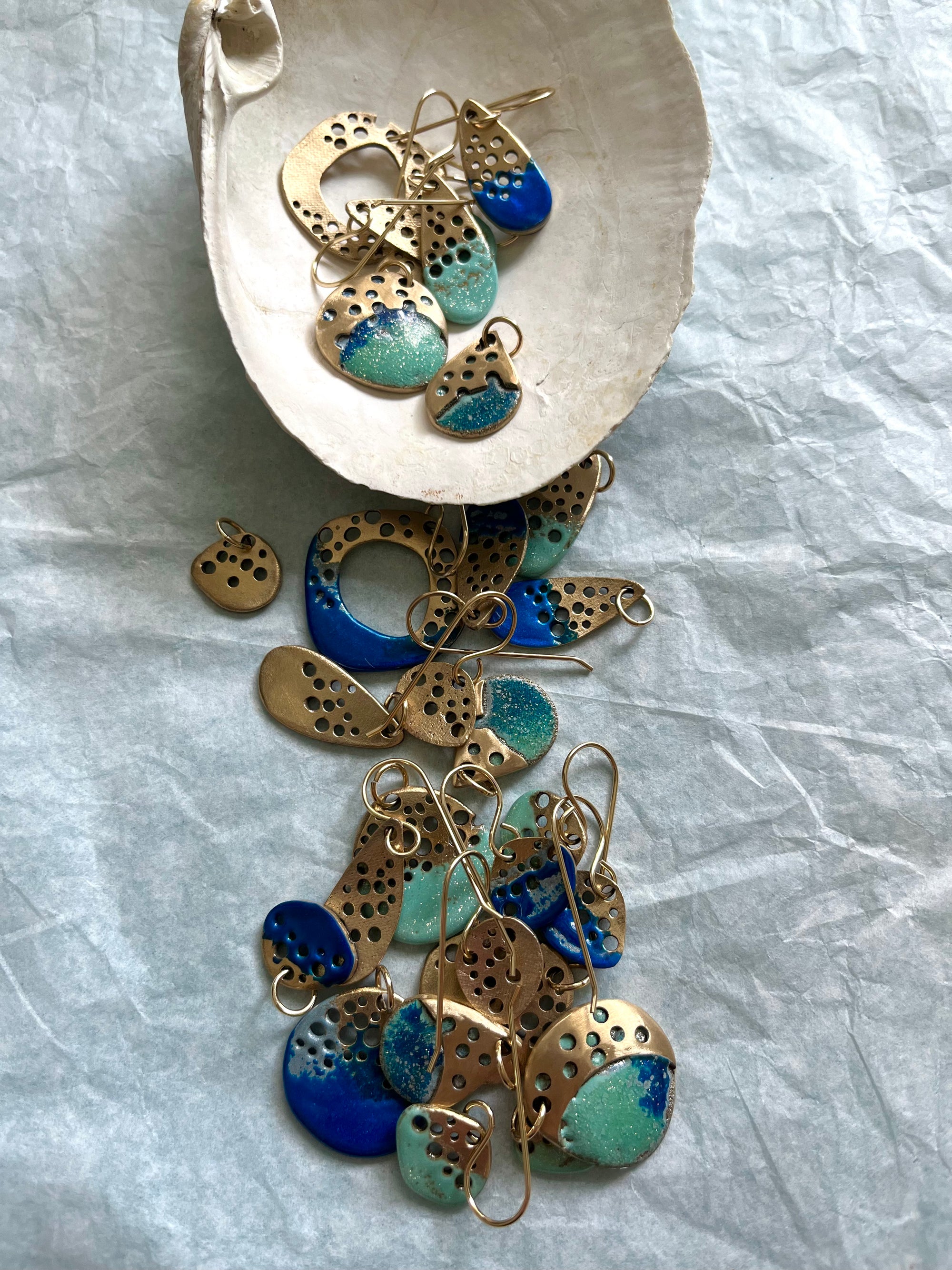 Ocean coloured bronze jewelry pieces tumbling from a seashell.