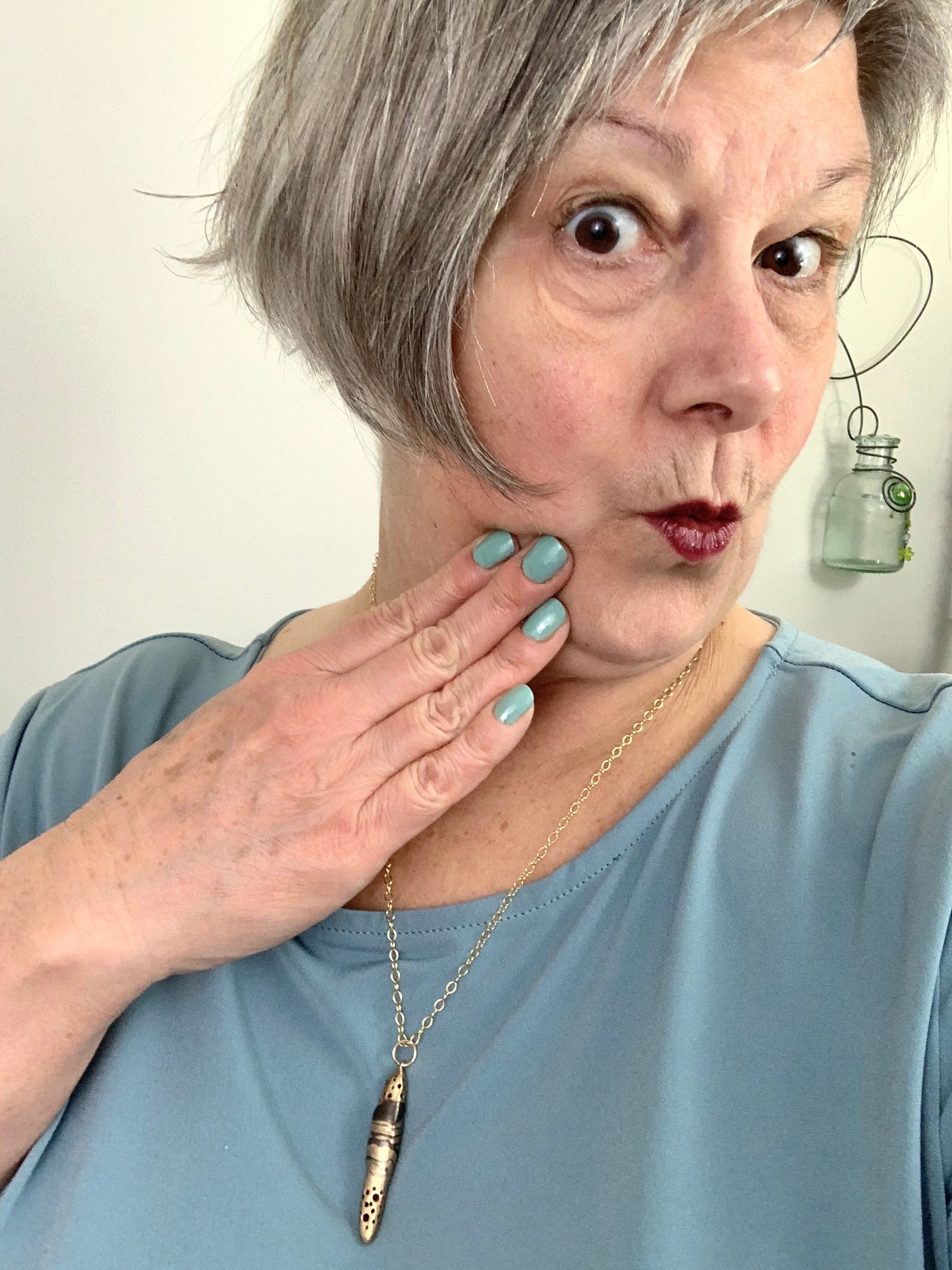 A surprised mid-life woman wearing art jewelry necklace